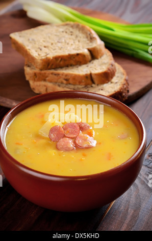 Erbsensuppe in Keramikschale auf Holztisch Stockfoto