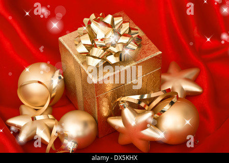 Nahaufnahme der Geschenk-Box mit goldenen Weihnachtskugeln über rote Seide Hintergrund. festliche Dekoration Stockfoto