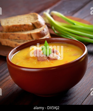 Erbsensuppe in Keramikschale auf Holztisch Stockfoto