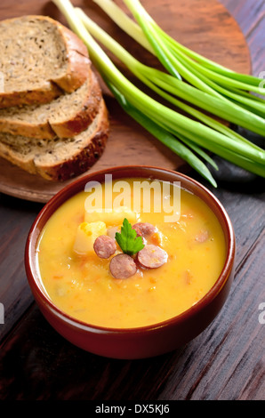 Erbsensuppe in Keramikschale auf Holztisch Stockfoto