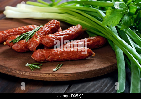 Geräucherte Würstchen mit Kräutern auf Holztisch Stockfoto