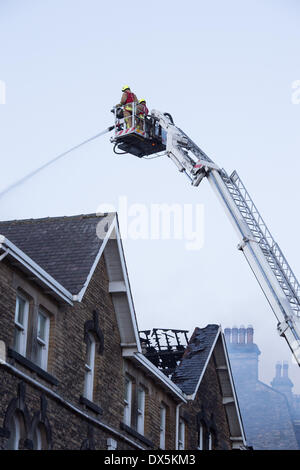 Mutige Feuerwehrmann Crew (2 Feuerwehrleute) hoch Leiter, bekämpfen das Feuer mit Wasser Schlauch am Zentrum Gebäude - Harrogate, North Yorkshire, England, UK. Stockfoto