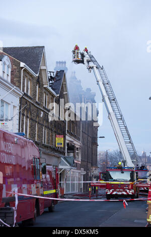 Mutige Feuerwehrmann Mannschaft hohe Leiter (vom Motor) Bekämpfung des Feuer mit Wasser am Zentrum Gebäude - Harrogate, North Yorkshire, England, UK. Stockfoto
