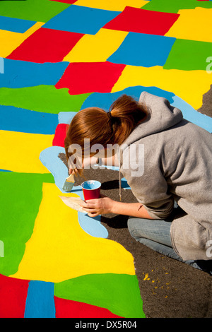 Ein junger Erwachsener freiwilliger Künstler malt den großen Seen auf einer Karte von den Vereinigten Staaten in einer Grundschule Spielplatz in Garden Grove, Kalifornien. Stockfoto