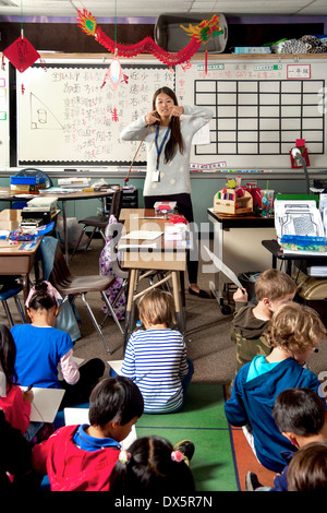 Ein asiatisch-amerikanische Lehrer führt eine erste Klasse Mandarin Chinesisch Sprachkurs in Laguna Niguel, CA. beachten Sie chinesische Schriftzeichen auf eine weiße Board und Drachen Marionette. Stockfoto