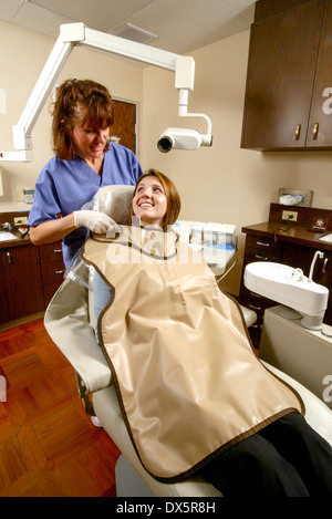 Zahnmedizinische Fachangestellte in Scrubs passt eine Bleischürze Sicherheit an einen Patienten vor der Durchführung einer Röntgenkontrolle auf ihre Zähne in Newport Beach, Kalifornien. Stockfoto