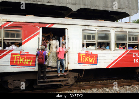 Menschen hängen von offenen Türen von s-Bahn Bahnhof Mount Lavinia in Colombo auf der Durchreise Stockfoto