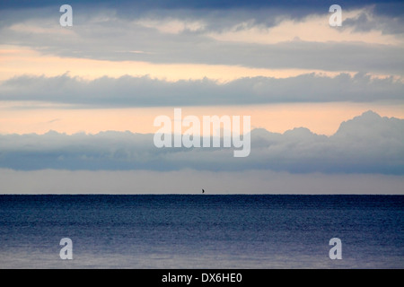 Seascape Vista mit dem Miniatur-Segelboot weit weg in den Horizont unter einem schönen frühen Morgenhimmel, Mosambik. Stockfoto