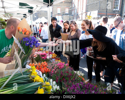 Frau mit Bargeld Kauf FrühlingsTulpen aus Glühbirne geschnitten Blumen Verkäufer Columbia Road Flower Market East London E2 England KATHY DEWITT Stockfoto