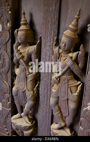 Spinnennetz bedeckt geschnitzte Holzfiguren auf Platten und Türen innerhalb der Shwe In Bin Kyaung Kloster, ein aus Teakholz in Mandalay Stockfoto