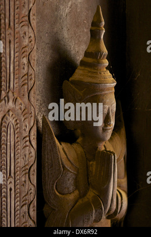 Ein Spinnennetz bedeckt geschnitzte Holzfigur auf Platten und Türen innerhalb der Shwe In Bin Kyaung Kloster, ein aus Teakholz in Mandalay Stockfoto