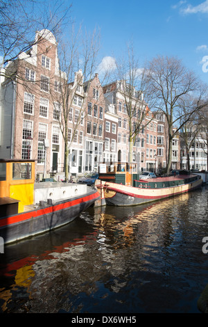 Kanal Lastkähne am Kanal in Amsterdam Niederlande mit historischen Lagerhallen im Hintergrund Stockfoto