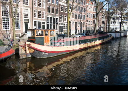 Kanal Lastkähne am Kanal in Amsterdam Niederlande mit historischen Lagerhallen im Hintergrund Stockfoto