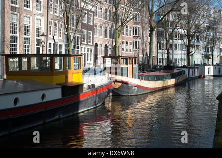 Kanal Lastkähne am Kanal in Amsterdam Niederlande mit historischen Lagerhallen im Hintergrund Stockfoto