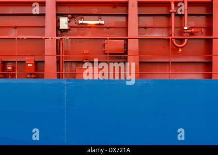 Rot und Blau erstrahlt an Bord Wand bildet einen interessanten strukturierten Hintergrund. Stockfoto