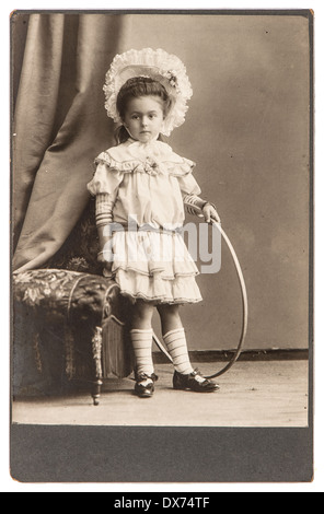 BERLIN, Deutschland - um 1900: altes Foto von kleinen Mädchen mit Spielzeug Vintage-Kleid tragen. nostalgisches Bild um 1900 in Berlin Stockfoto