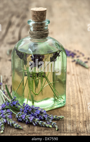 pflanzliches ätherisches Lavendelöl mit frischen Blumen auf hölzernen Hintergrund Stockfoto