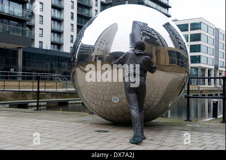 Skulptur im neuen Dock, ehemals Clarence Dock, Leeds, zeigt Leben Größe Bronze Figur schieben Edelstahlkugel. Stockfoto