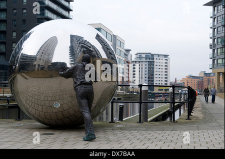 Skulptur im neuen Dock, ehemals Clarence Dock, Leeds, zeigt Leben Größe Bronze Figur schieben eine Kugel aus Edelstahl. Stockfoto