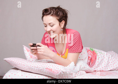 Das Mädchen im Bett liegend und am Telefon sprechen Stockfoto