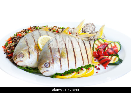 Pompano Fisch vom Grill mit Wildreis, Gemüse und Austern auf einem weißen Hintergrund. Stockfoto