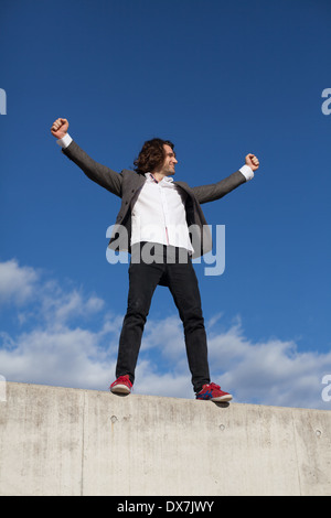 Eine junge männliche Modell auf eine Betonmauer mit blauem Himmel hinter Stockfoto