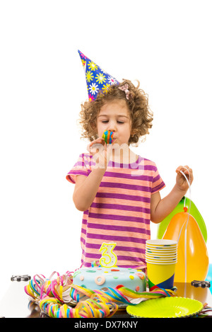 Mädchen Geburtstag Alter von drei Jahren aus und bläst in eine Partei Horn isoliert auf weißem Hintergrund Stockfoto