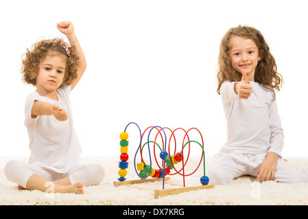 Mädchen sitzen auf Fell Teppich mit Holzspielzeug und Daumen aufgeben nach Hause Stockfoto