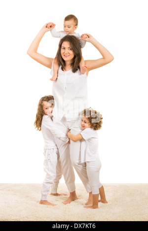 Schöne starke Mutter mit drei Kindern auf Teppich zu Hause stehen Stockfoto