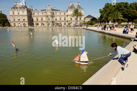 Jungen spielen mit Spielzeugboot auf einem Teich bei einem Paris-Palast Stockfoto