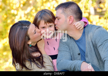 Glückliche Mutter und Vater ihrer Tochter im Park küssen Stockfoto