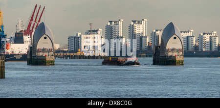 Schlepper mit Ladung durch die Themse-Sperrwerks mit einer Kulisse aus high-Rise Wohnungen in Woolwich, South East London Stockfoto