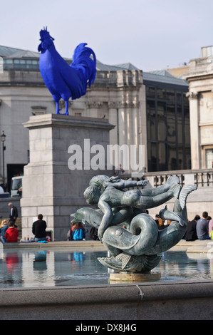 Die Skulptur der Meerjungfrauen und Delfine am Wasserbrunnen mit ein riesiger blauer Hahn im Hintergrund auf dem Trafalgar Square. Stockfoto