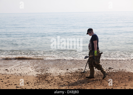 Ein Mann mit Metalldetektor am Gewässerrand Meer Strand. Stockfoto