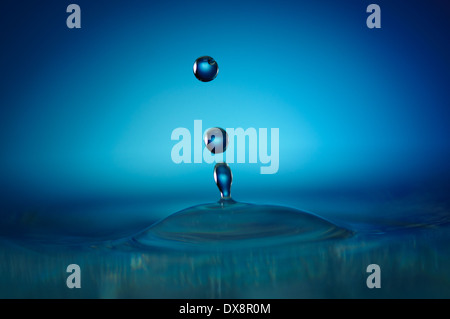 Drei blaue Wassertropfen bilden abstrakte Figur ohne Spritzer Stockfoto