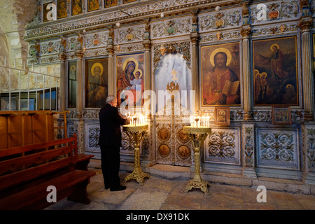 Ein arabisch-christlicher Verehrer zündet Kerzen an der Johannes-Kapelle und Taufkapelle im Innenhof der orthodoxen Jakobskapelle, die auch als Kirche von Mar Jacob oder St. Jakobs orthodoxe Kathedrale neben der Grabeskirche bezeichnet wird, An der westlichen Wand des square.in Christlichen Viertels Altstadt Ost-Jerusalem Israel Stockfoto