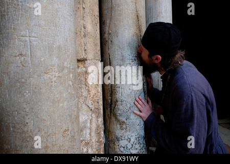 Eine christlich-orthodoxer Priester küssen die Spalten die Kreuzritter Graffiti, meist bestehend aus Kreuze am Eingang der Heilig-Grab-Kirche in Christian Quarter alte Stadt Ost-Jerusalem Israel fallen Stockfoto