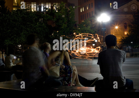 A Street Performer in NYC Tänze für die Zuschauer mit einer flammenden Hula-Hoop im Washington Square Park in einer Sommernacht Stockfoto