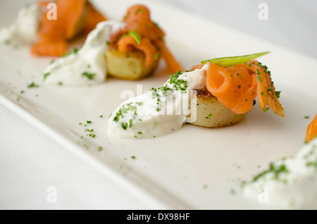 Geräucherter Lachs auf Bratkartoffeln mit Kräuter-Joghurt und gehackter Petersilie. Stockfoto