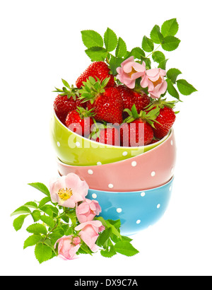 Erdbeeren und bunten Schalen mit rosa Rosen Blumen Dekoration auf weißem Hintergrund Stockfoto