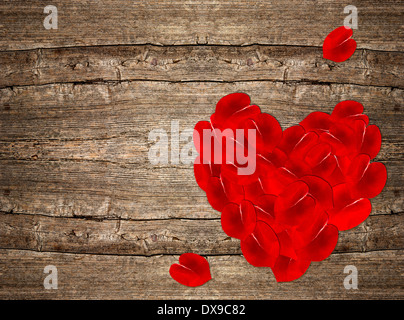 rote Rosenblätter in Herzform über rustikalen hölzernen Hintergrund. Valentinstag Hintergrund Stockfoto