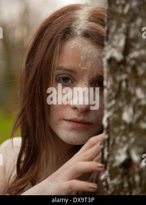 Teenager-Mädchen hinter Baum mit Mehl auf ihrem Gesicht peering Stockfoto