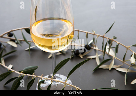 Glas Weißwein, Filiale von schwarzen Oliven, Rosmarin und Olivenblätter Stockfoto