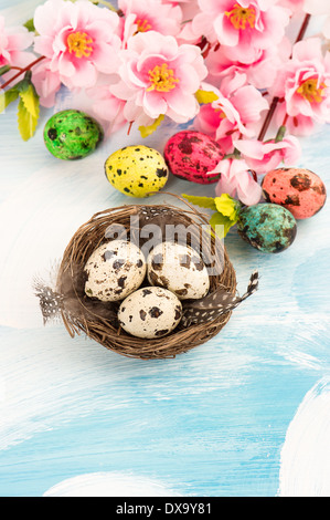 Oster-Deko mit Blumen und Eiern im Nest. Handgefertigte farbige Wachteln Eiern Stockfoto