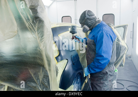 Eine professionelle Auto-Maler, der die Karosserie eines Autos in einen Malkasten einer Garage mit einem Airbrush Malerei ist. Stockfoto