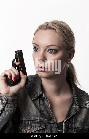 Blonde Frau hält Pistole und schaut sich um, tragen Jeansjacke. Stockfoto