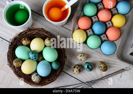 Erhöhte Ansicht Osterei zu sterben. Gefärbten Eiern in ein Nest mit Eiern in Farbstofflösung und anderen Eiern gerne getaucht werden. Stockfoto