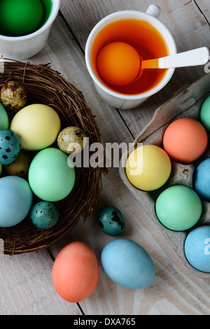 Erhöhte Ansicht von Ostereiern sterben. Gefärbten Eiern in ein Nest mit Eiern in Farbstofflösung. Hochformat auf einem rustikalen Bauernhof-Tisch Stockfoto