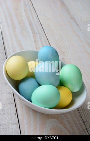 Vertikale hohen Winkel Schuss einer Schüssel Pastell Ostereier. Die weiße Schale ist voll von gelb, grün und blau gefärbten Eiern Stockfoto