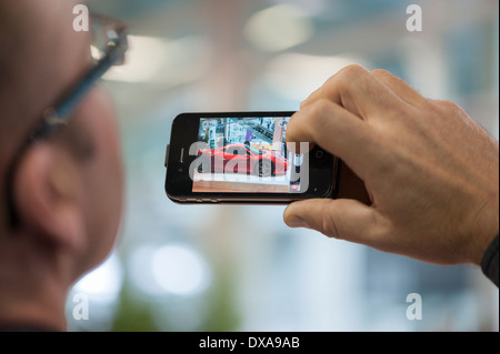 Ein Besucher der Zürich Motor Show in Zürich nimmt ein Bild von einem Ferrari F458 Speciale-Luxus-Sportwagen mit seinem iPhone Stockfoto